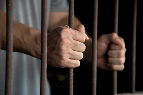 addiction treatment vs. prison - hands jail cell bars - willingway