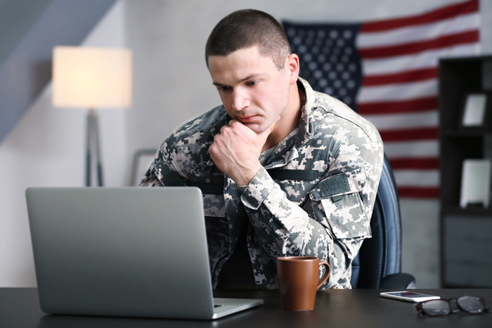 military man in office looking at laptop