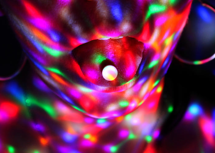 ecstasy, club drug, closeup of pill on person's tongue; brightly colored lights reflect on their face - club drugs