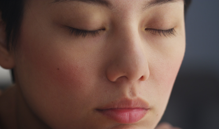 closeup of Asian woman with her eyes closed - mindfulness