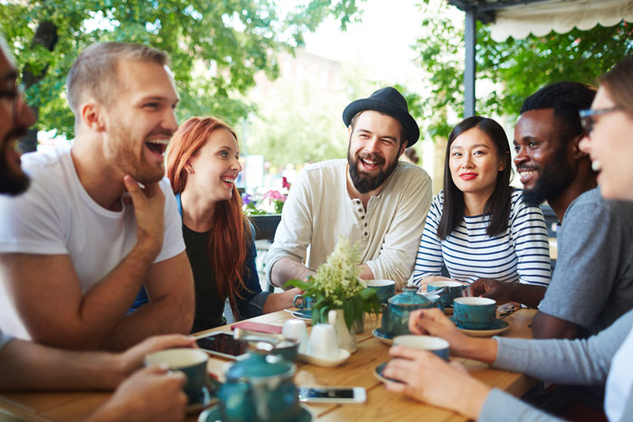 group of diverse friends having coffee at outdoor cafe together - sober living
