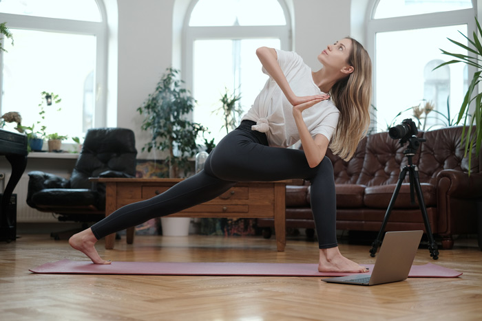young woman doing an advanced yoga pose at home - holistic therapies