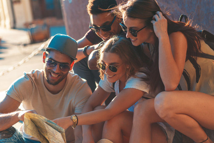 two couples or four friends smiling and looking at a map together - vacation